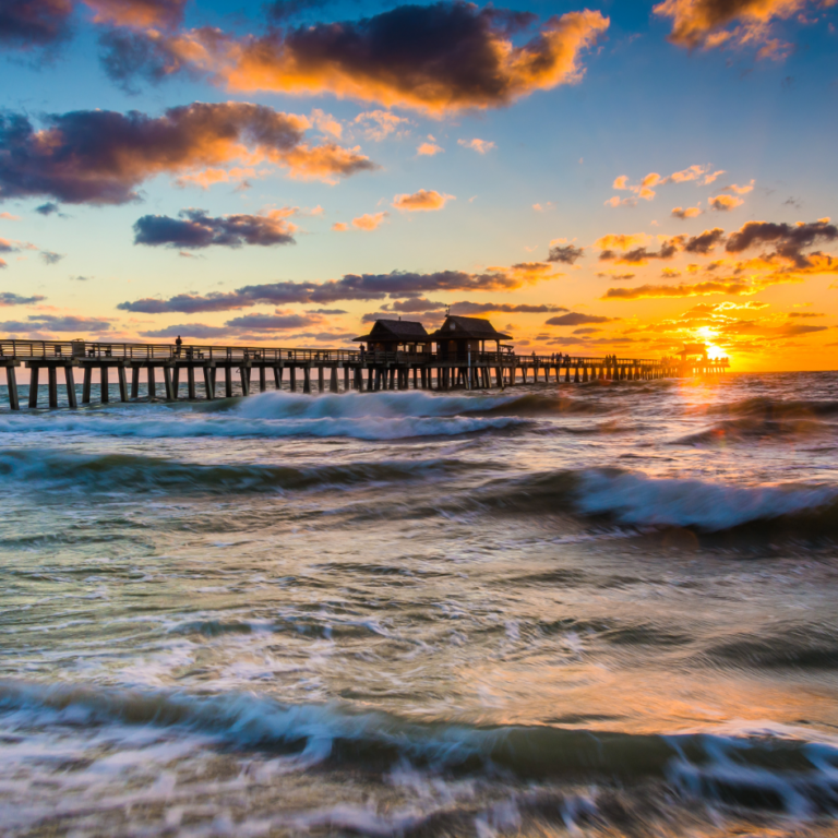 Sunset over a Gulf Coast fishing pier with crashing waves, colorful clouds, and coastal scenery along the Mississippi Gulf Coast.