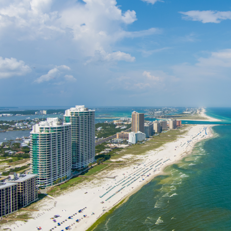 Aerial view of Orange Beach Alabama featuring white sand beaches, Gulf Coast condos, turquoise water, and coastal shoreline along the Gulf.