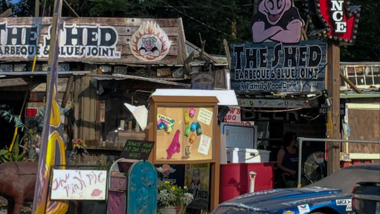 Exterior view of The Shed BBQ & Blues Joint in Ocean Springs Mississippi, a nationally known Gulf Coast barbecue restaurant famous for slow smoked BBQ, rustic decor, and unique junkyard style appearance.