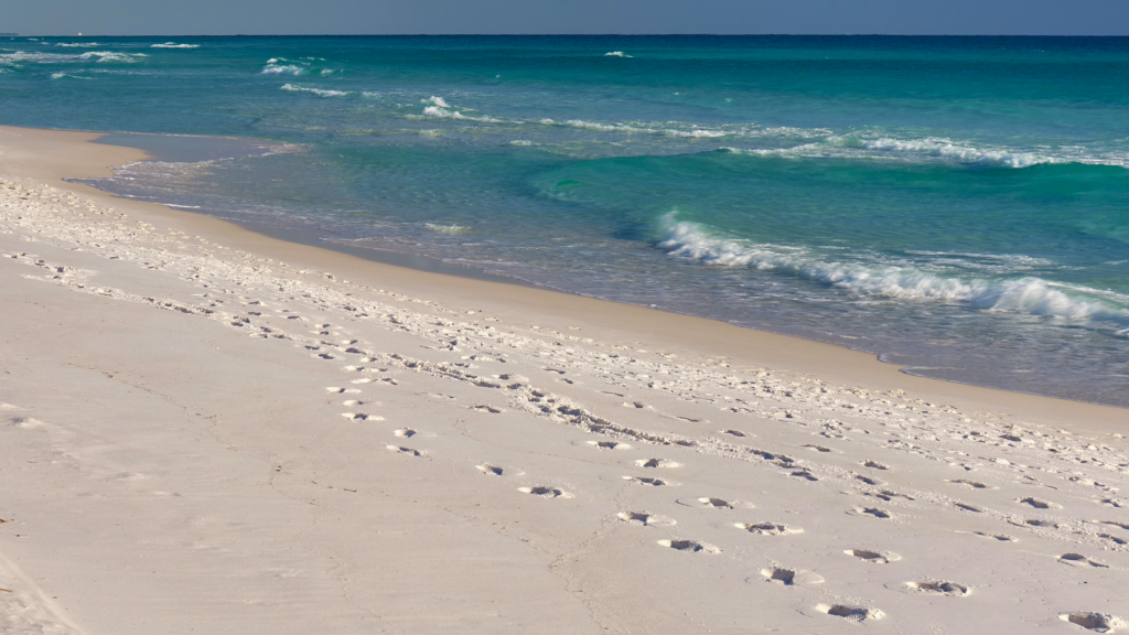 Bright white Gulf Coast beach sand along the shoreline at sunset representing the surprising geological history of quartz sand found on Gulf Coast beaches in Alabama, Mississippi, and Florida.